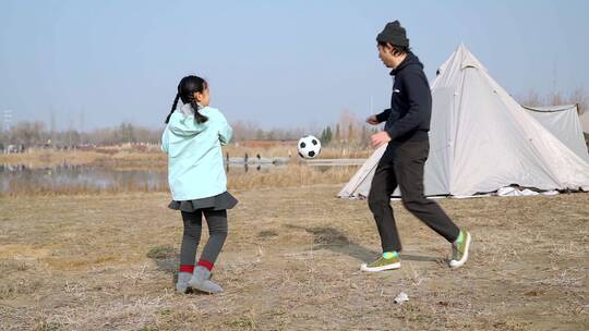 冬季在户外和女儿踢球的父亲