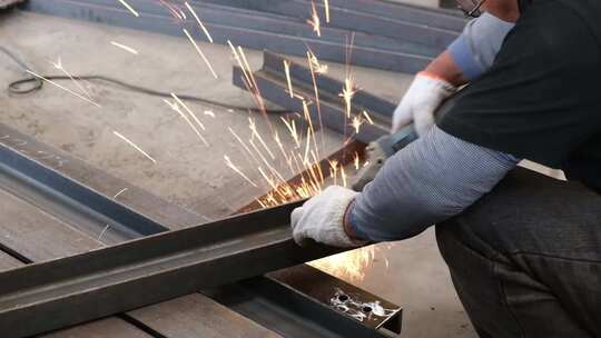 工厂车间工人使用角磨机打磨钢板