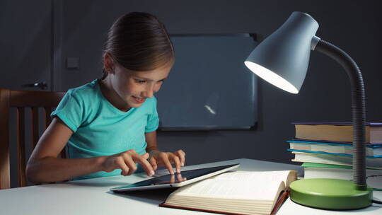 小女孩在灯下使用平板电脑