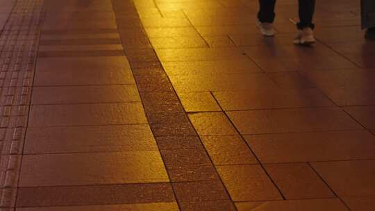 暖色灯光下路人行走的脚步