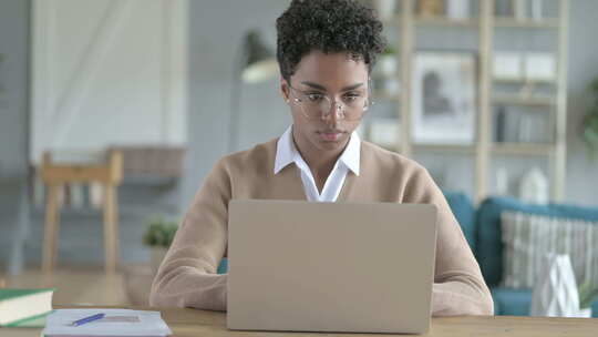 工作的非洲女孩在桌子上使用笔记本电脑