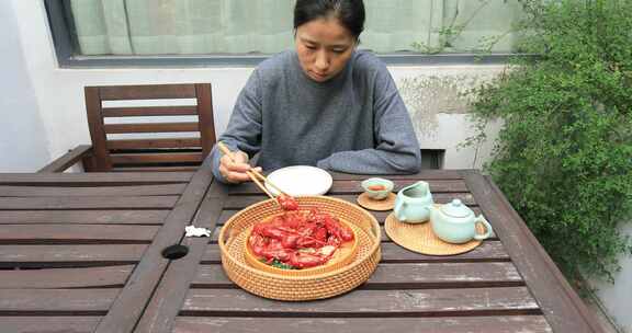 年轻女子在院子里开心吃龙虾