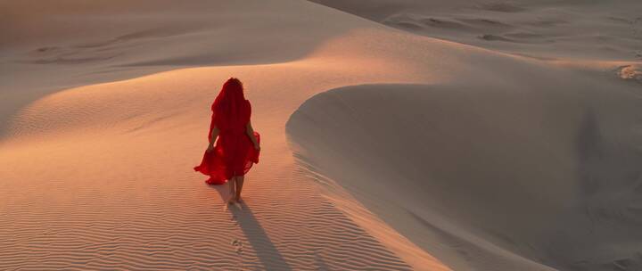 航拍沙漠中行走的红衣女子