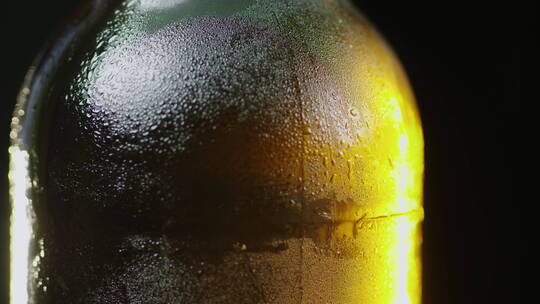 一瓶慢慢旋转的玻璃瓶上凝结的水滴向下流动