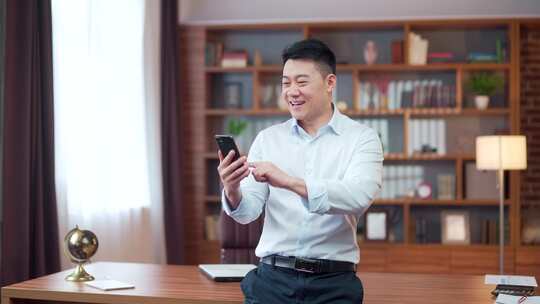 激动的亚洲商人手持智能手机喜出望外的商人视频素材模板下载