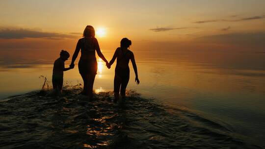 幸福的一家人三口海边散步看夕阳晚霞