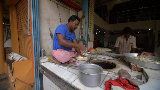 厨师坐在灶台做烙饼