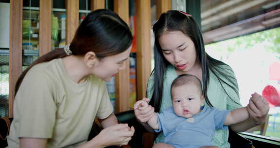 两个年轻的亚洲女人在咖啡馆里开心地和一个