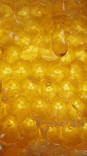 垂直视频。蜂蜜滴落天然金色蜂蜡梳，宏观视