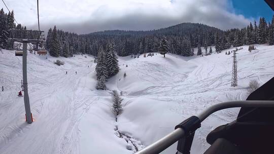 POV拍摄的滑雪者在椅子上电梯穿过积雪覆盖的山