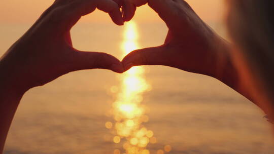 情侣在日落时分的海边比心