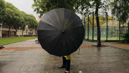 雨中欧洲城市路灯上带伞和雨衣的商人游客