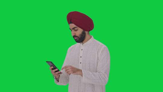 严肃的锡克教印度人使用手机绿屏