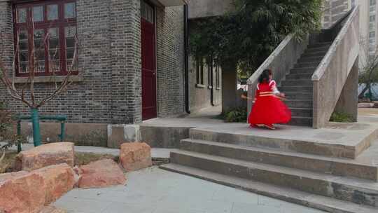 穿着红色喜庆服饰走下楼梯开心转圈的小女孩