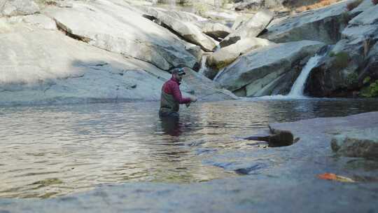 静态拍摄，人在花岗岩峡谷齐腰深的水中飞钓