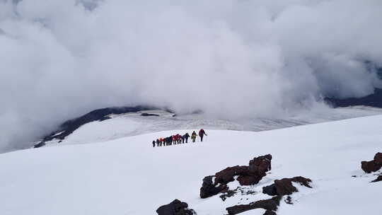 一群登山者在山顶上行走登山队攀登雪山