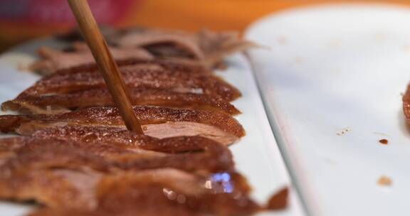 用筷子夹起一块烤鸭鸭肉
