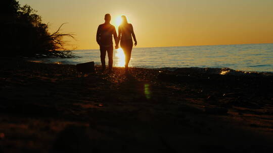 夕阳海滩上牵手漫步的夫妇