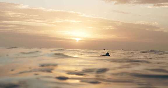 日出时分冲浪者游向海洋波浪海浪翻滚