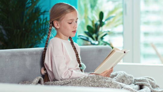 女孩坐在沙发上看书