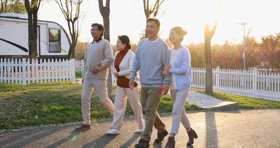 夕阳下中老年夫妻手挽手在露营地聊天散步