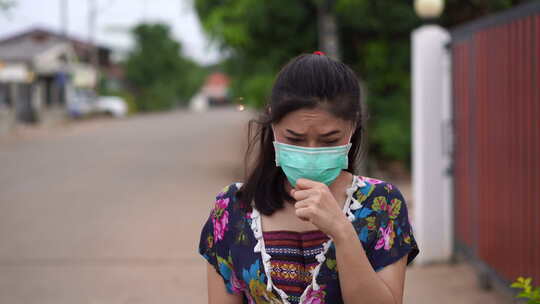 戴医用口罩（外科口罩）走路和咳嗽的年轻女