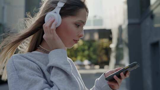 时尚女性将无线耳机与智能手机连接以听音乐视频素材模板下载