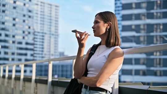 年轻女子在智能手机上录制音频信息户外城市