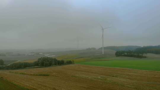 航拍接近风电场，雾中的风车，周围的灰色景观，可再生能源i
