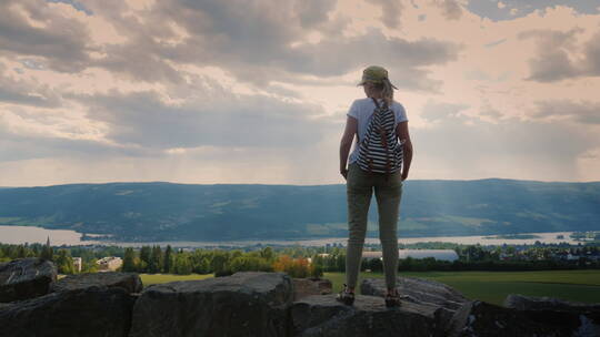 女旅行者站在高处的岩石上眺望