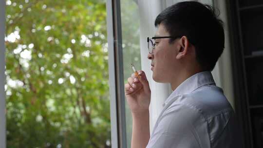 男子思考窗边抽烟