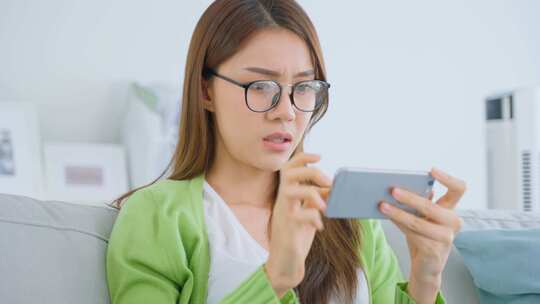 亚洲沮丧的电子竞技游戏玩家在家里用手机玩手机游戏时感到愤怒。