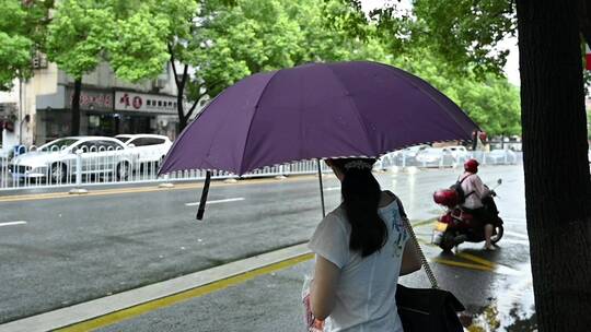 下雨天等公交的市民