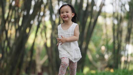 小女孩快乐奔跑在公园竹林小径