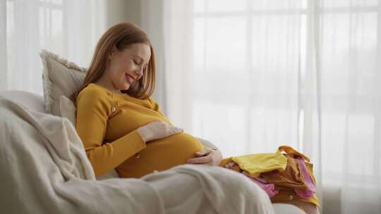 孕妇看婴儿玩具积极的未来母亲享受产妇看婴