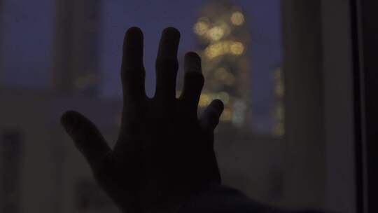 悲伤孤独的人在夜晚触摸玻璃窗外美景