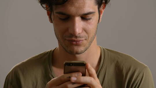 年轻英俊的男人微笑着在智能手机上打字