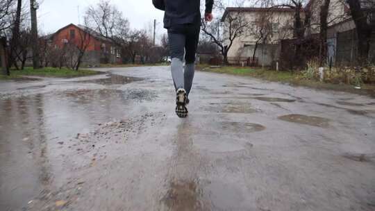 雨天沿乡村小径跑步的年轻运动员的腿运动跑