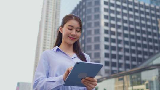 站在城市里使用数字平板电脑的亚洲年轻女商