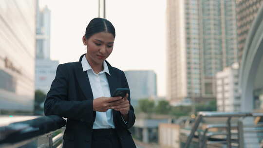 穿着办公室服装站在外面打电话的亚洲女人