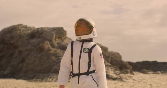 男孩穿着宇航服在沙滩行走