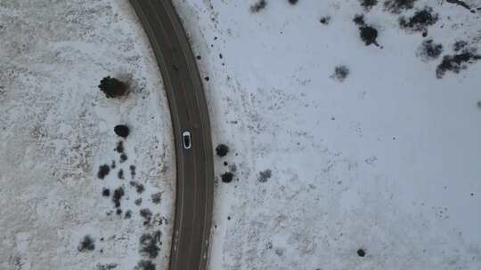 航拍新能源汽车行驶在冬季雪景公路上