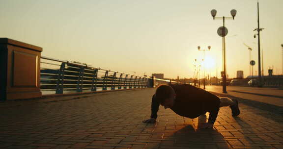 日落时分，年轻运动员在城市街道上做俯卧撑