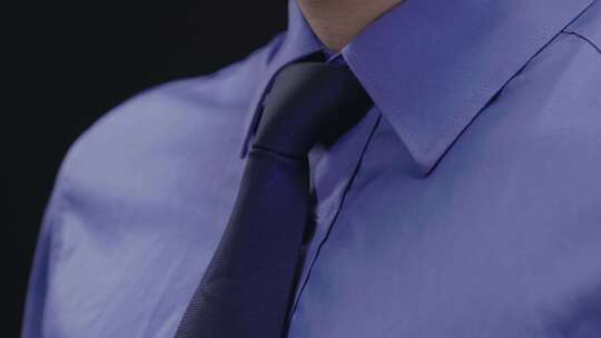 穿蓝色衬衣的男人整理领带