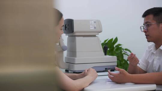 男验光师为年轻女顾客提供仪器眼科验光服务
