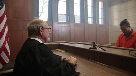 法庭上有法官和橙色连身衣囚犯