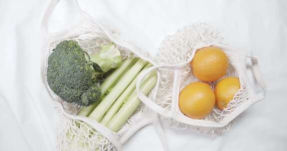 装蔬菜瓜果，袋子里的花椰菜和橙子