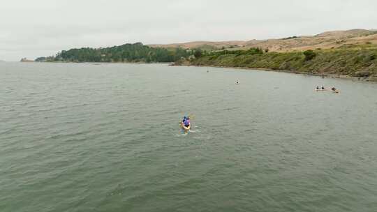 超车镜头，人们划着皮划艇快速前进，驶向加利福尼亚州巴伊亚托马莱斯美丽的海岸