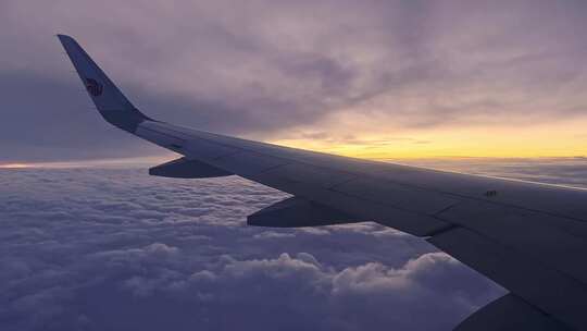 夕阳下民航飞机在云层之上飞行