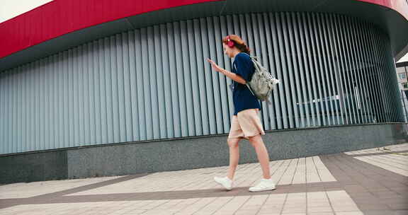 美丽的年轻女子学生带着背包和电话在户外跳